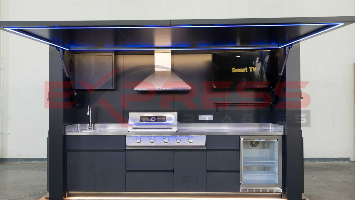 Modern kitchen setup on a pallet with appliances and a TV screen. Outdoor BBQ Pod with fridge, tv, electric spice cabinet, self-watering herb garden, soft close drawers, rangehood, 4 gas burner.